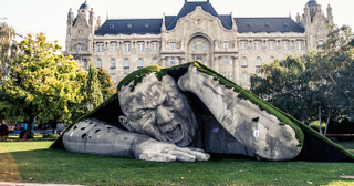 Illustration for article titled Scary giant man crawls out from the ground in shocking outdoor sculpture